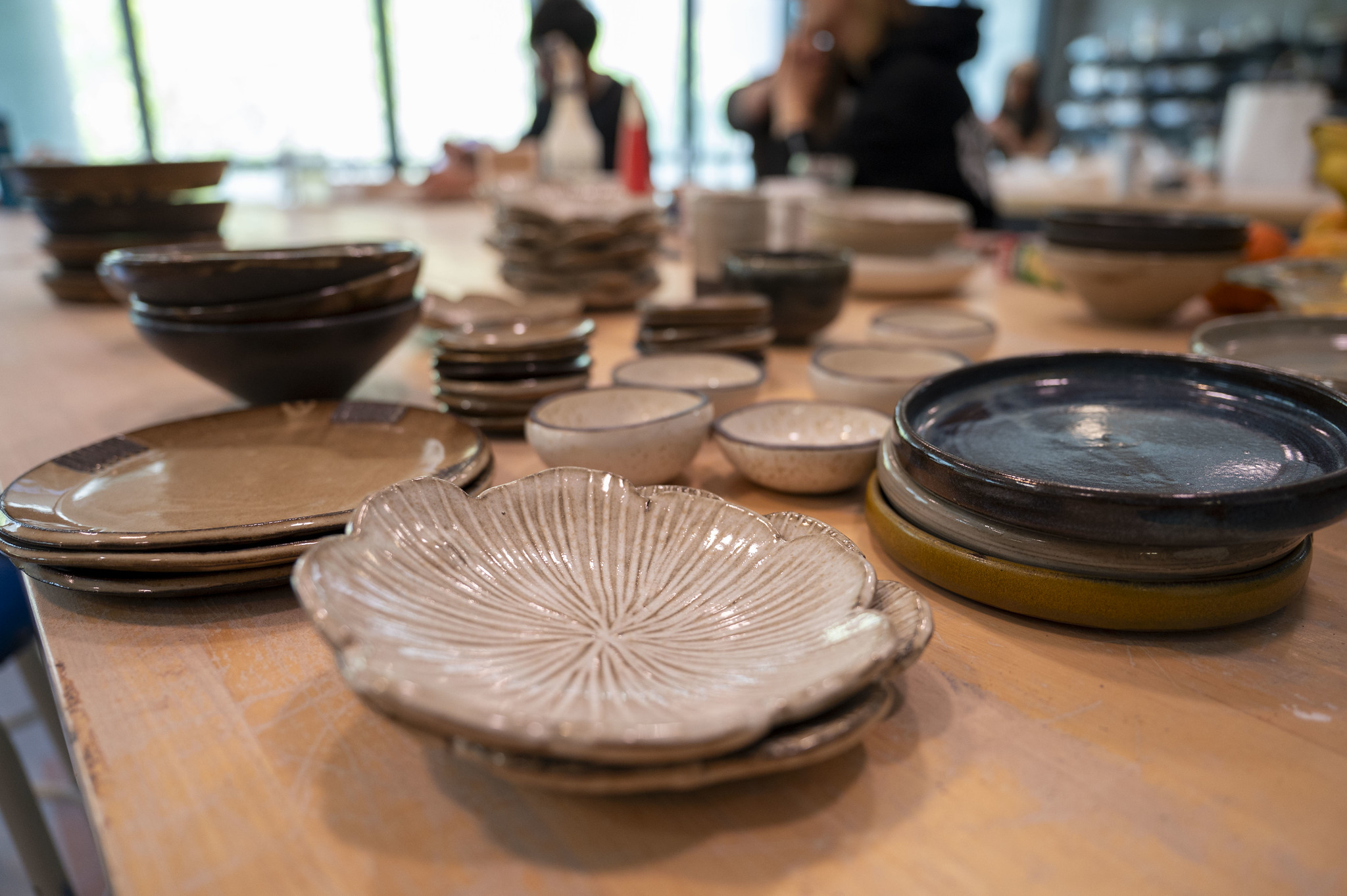 Handmade ceramic plates and bowls produced by ceramics students are displayed in the campus studio.