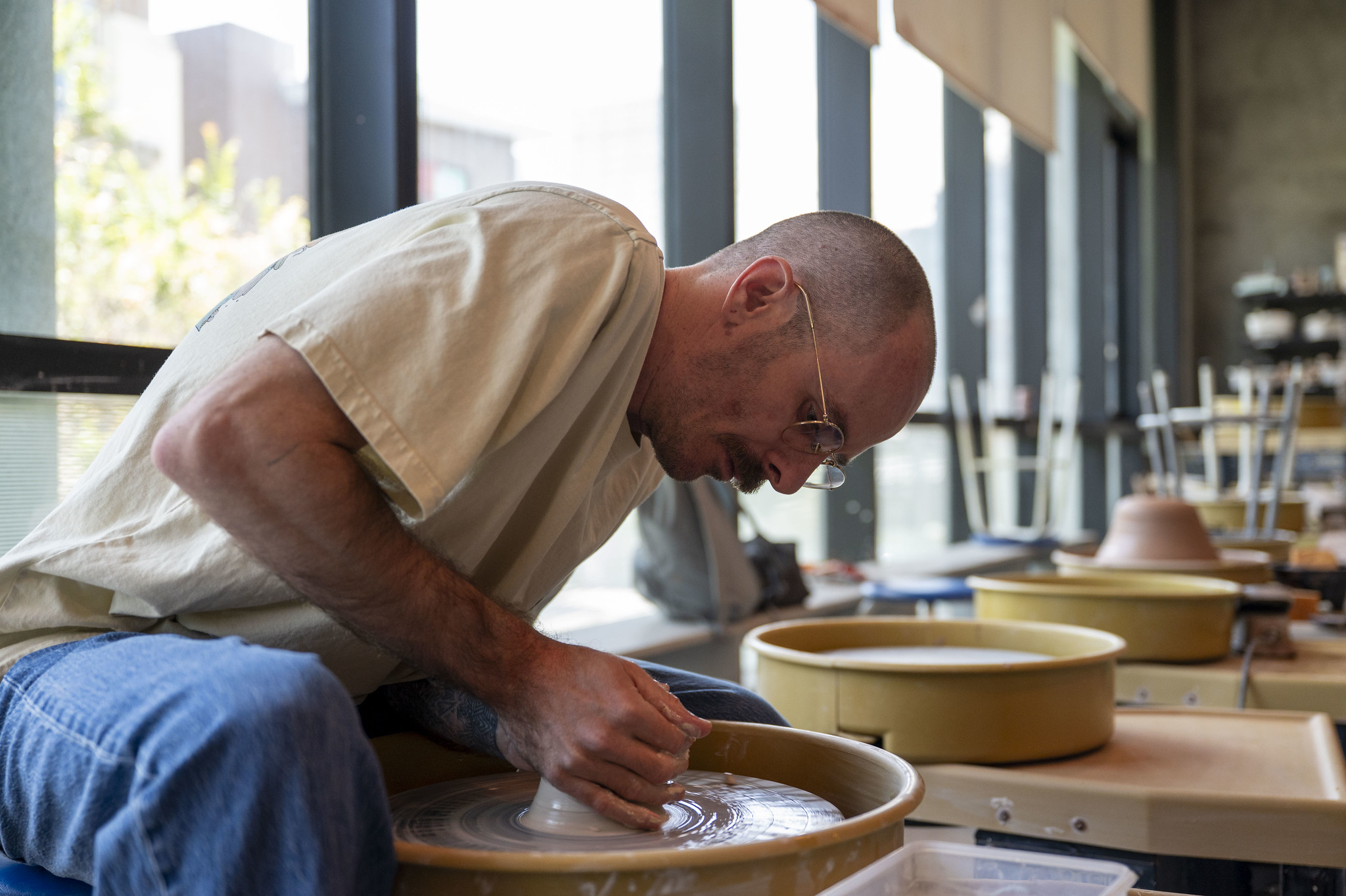 Scott Beach shapes clay on the pottery wheel in the City College ceramics studio.