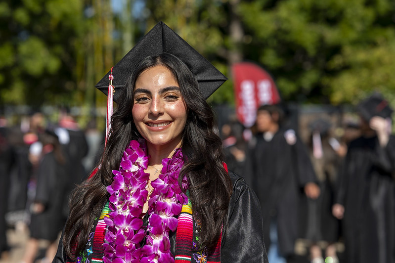 Woman smiling with cap and gown and flower lei